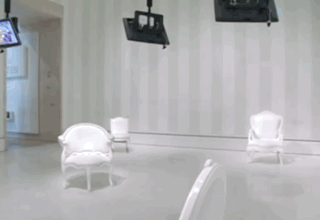 Two white chairs floating in a flooded room with a TV mounted on the wall.
