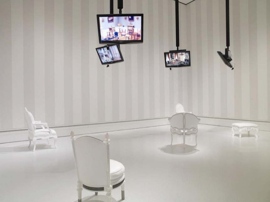 Please Be Seated, an interactive video installation with white furniture and suspended monitors at the J. Paul Getty Museum